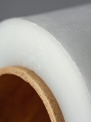 Roll of transparent polyethylene cling film on gray background