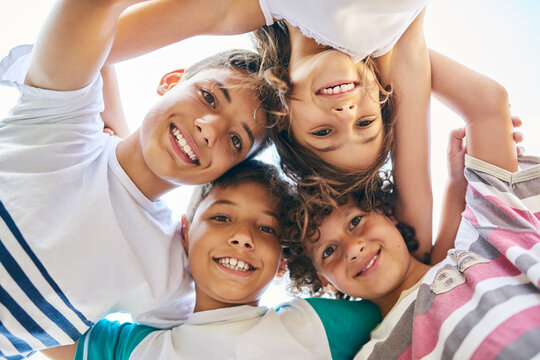 Portrait, low angle and a group of happy siblings or huddled together or hug in solidarity and smiling outdoors. Circle, brothers and sisters or excited children play or bonding and face outside