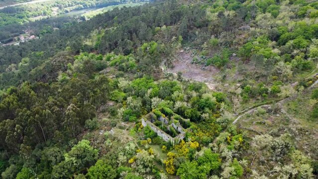 Aerial orbit Landscape shot of the ruins of the Santa Comba de Naves monastery in the forest at Ourense, Spain