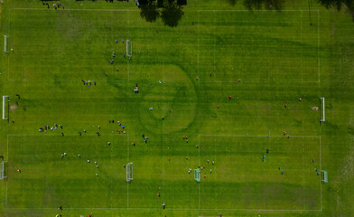 sports stadium forball match with several goals. the children here have a series of elimination school grade matches. observe the swarm vertically downwards. mowed stripes lawn