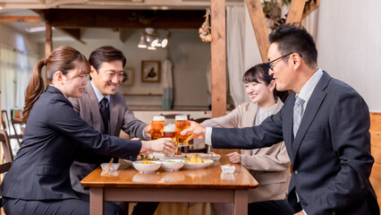 居酒屋で忘年会・新年会・飲み会・宴会をする仕事仲間・同僚・上司部下の男女
