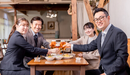 居酒屋で忘年会・新年会・飲み会・宴会をする仕事仲間・同僚・上司部下の男女
