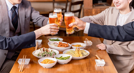 居酒屋で忘年会・新年会・飲み会・宴会をする仕事仲間・同僚・上司部下の男女
