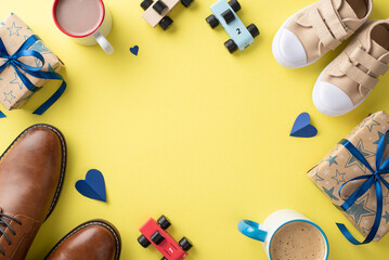 Son cheers on Dad for Father's Day. Top-down view of father's dress shoes, son's small sneakers, hearts, tea mugs, toys, and gift boxes on yellow background with space for text or advertising