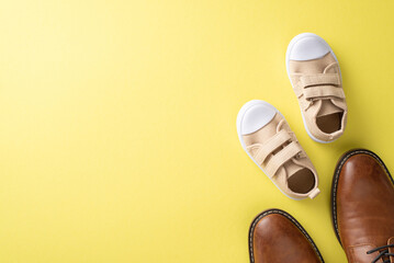 Father's Day idea with cute son and dad. Top view of leather shoes and baby sneakers on yellow...