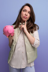 young brunette woman decides where to invest her savings from the piggy bank