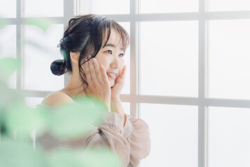 Fototapeta premium 家でスキンケアする頬を触る笑顔のアジア人女性 