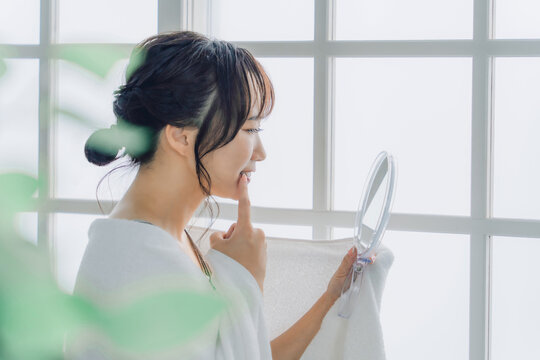 鏡で歯を見て困るアジア人女性（虫歯・歯並び・歯周病）
