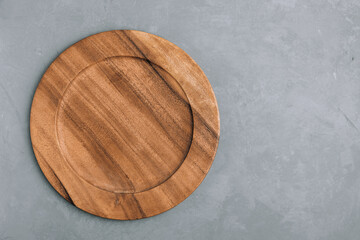 Wooden plate. Empty round wooden plate on gray stone background