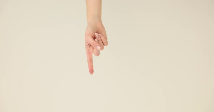 Woman hand shows downward direction using forefinger standing in premise. Index finger of hand indicates direction on light background slow motion