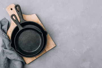 Empty pans. Cast iron pans on wooden chopping board with napkin.