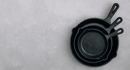 Empty pans. Cast iron pans on gray stone background, top view, copy space.
