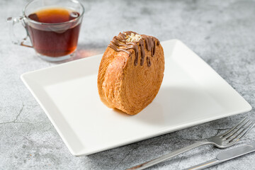 Chocolate New York roll or round croissant with tea on stone table