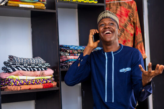 overexcited african businessman making call with his mobile phone, wearing Africa attire