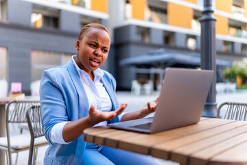 Young entrepreneur is not satisfied with the work of the company, she has a business meeting via laptop while sitting outside, casually dressed for business