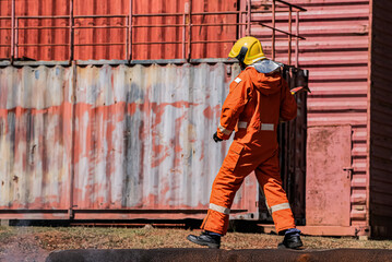 In the outdoor setting a firefighter stands sideways their body positioned with a sense of alertness and readiness while firmly gripping an iron axe.