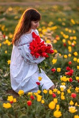 Woman field tulips sunset. Woman against sunset and wild tulip flowers, natural seasonal background. Multi-colored tulips Tulipa schrenkii in their natural habitat are listed in the Red Book.