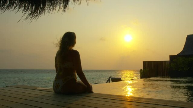 Woman watches sunset from luxury tropical villa
