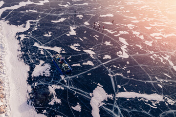 Hovercraft with tourists parked on clear ice in winter Lake Baikal, aerial top view