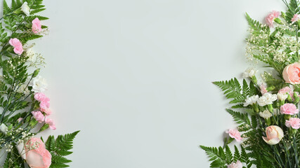 Beautiful floral frame of fresh flowers with pink rose, carnation and fern leaves with copy space for text on blue background