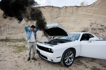Shocked man is standing near his broken muscle car, open hood, smoke from engine,  breakdown, need...