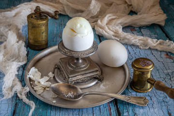 Two white chicken eggs, an egg cup, a pepper mill and a salt shaker. Breakfast.