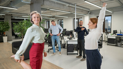 Fototapeta na wymiar Four office workers warm up during a break. Employees do fitness exercises at the workplace. 