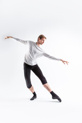 Caucasian Handsome Young Man Dancing Ballet Posing in Ballet Pose with Lifted Hands in White Shirt On White.