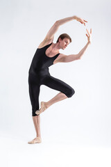 One Professional Male Ballet Dancer Young Man in Black Dance Tights Suit Posing in Ballanced Dance Pose in Studio.