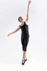 Fototapeta premium Contemporary Ballet Dancer Flexible Athletic Man Posing in Black Tights in Ballanced Dance Pose With Hands Lifted