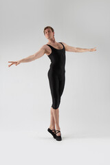 Fototapeta premium Male Ballet Dancer Flexible Athletic Man Posing in Black Tights in Ballanced Dance Pose With Hands Horizontal
