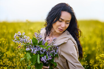 Naklejka premium portrait of a brunette woman in a rapeseed field in spring
