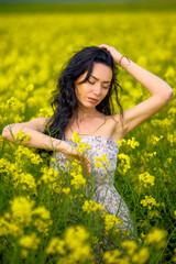 portrait of a brunette woman in a rapeseed field in spring