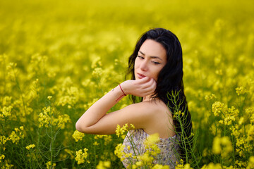 portrait of a brunette woman in a rapeseed field in spring