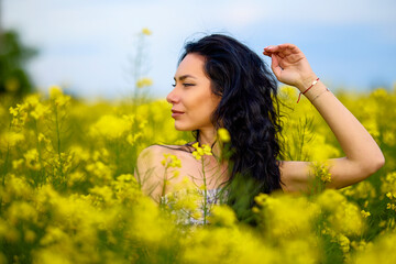 portrait of a brunette woman in a rapeseed field in spring