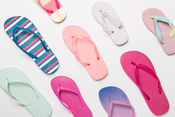 Many bright flip flops on color background, top view