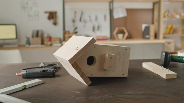 Medium shot of wooden handmade birdhouse on workbench in carpentry workshop with no people there