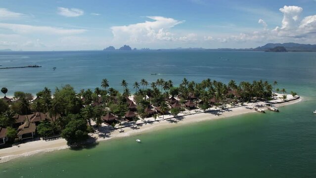 Drone footage of view of beach cape of Koh Mook island including coconut trees and the boats float outside the beach. blue clear sky and ocean sea view. resorts for tourism.