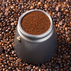 Kawiarka postawiona na palonych ziarnach kawy