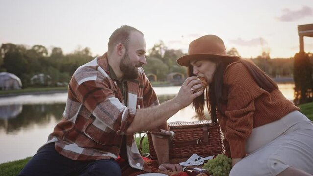 Happy man feeding pregnant woman during picnic