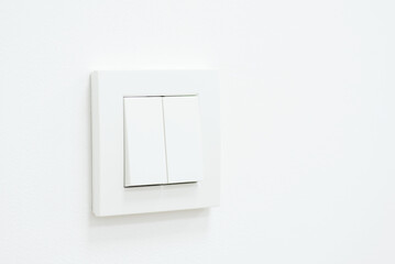 Minimalist photo of a white light switch on a wall. Turned on light switch on a white wall