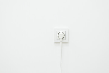 White wall with plug in it. Using electricity concept, wall outlet with connected device