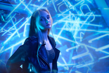 Portrait of young beautiful girl in leather jacket posing over blue background with abstract neon elements. Night life. Concept of art, modern style, cyberpunk, futurism and creativity