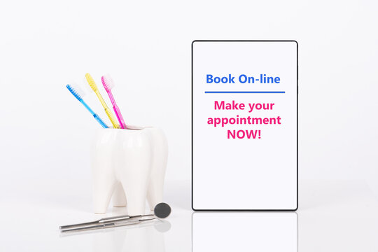 Dentist appointment date or any other dental message on tablet, ceramic tooth with three bright colors toothbrushes and dental tools mock up. White background.