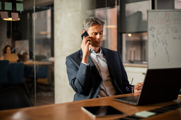 Businessman in office. Handsome man talking on phone at work..