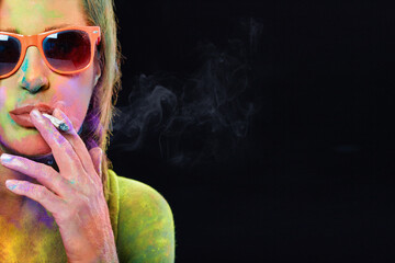 Beautiful woman covered in rainbow colored powder smoking weed cigarette