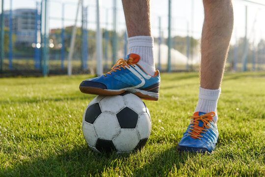 Legs of a male football player on soccer ball at stadium, close up