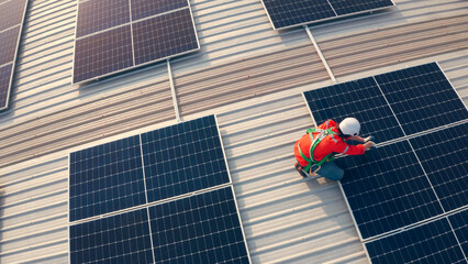 Male engineer maintaining solar cell panels on building rooftop. Technician working outdoor on...