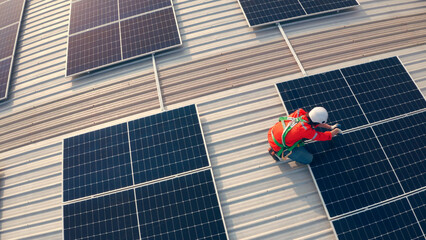 Male engineer maintaining solar cell panels on building rooftop. Technician working outdoor on ecological solar farm construction. Production of renewable energy concept.