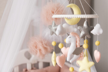 Toys over the crib. A mobile baby cot with stars, clouds and a unicorn.